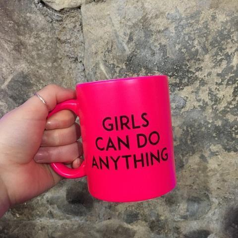 Person holding pink mug that says girls can do anything.